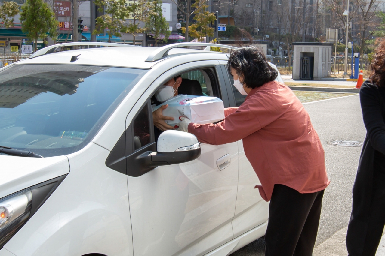 세종시 아름중 교사가 23일 차를 타고 방문한 학부모에게 교과서를 전달하고 있다. (사진=세종교육청)