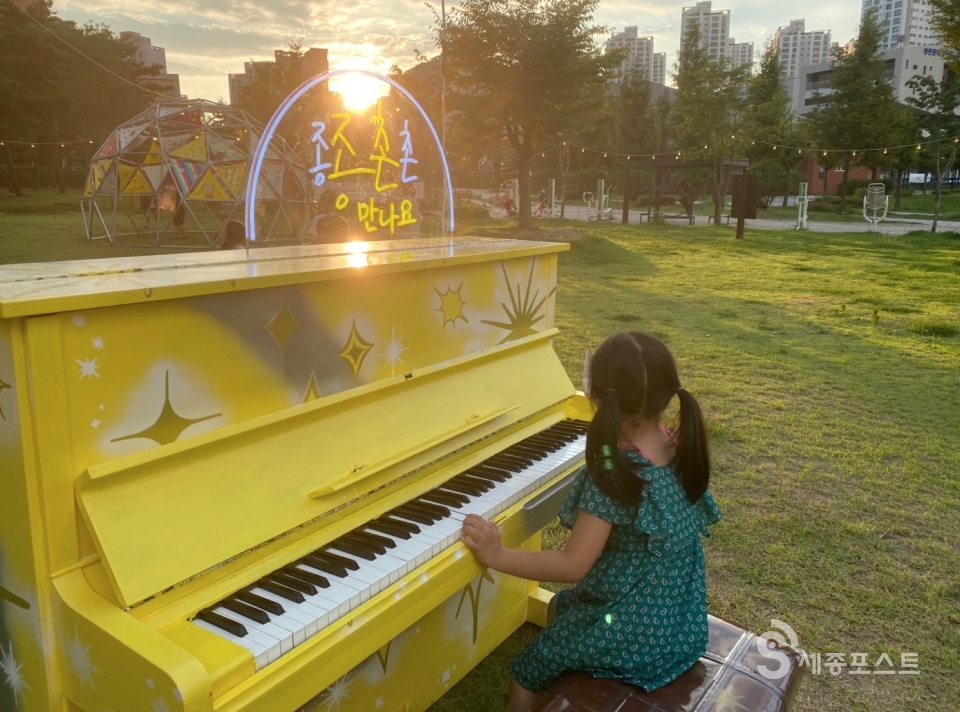 종촌동 상생형 문화거리에 마련된 노란색 피아노 앞에서 피아노를 치고 있는 한 어린이 ⓒ정은진 기자