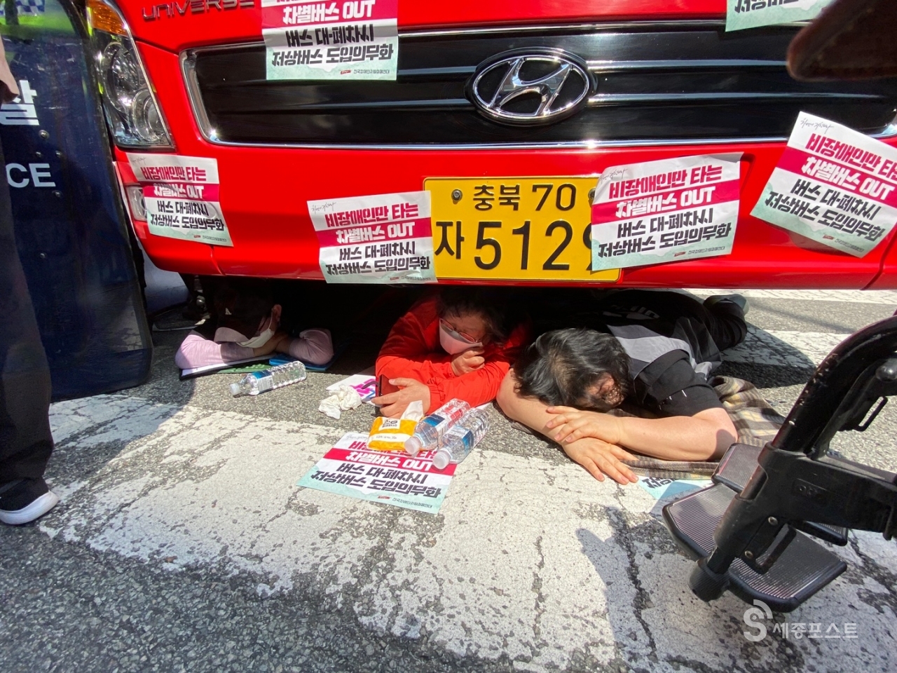 장애인차별철폐 회원들이 바로타 버스 아래로 들어가 장애인 철폐를 촉구하고 있다. ⓒ정은진 기자<br>
